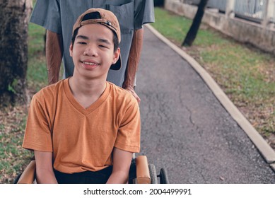 Happy asian disabled teen boy on wheelchair smiling face as happy with parent in the nature outdoors park, Lifestyle in the education age of special need kid, Diverse people concept.