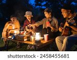 Happy asian diverse group friends enjoy drinking a beer together. They feeling relaxed and refreshing while camping in the nature at night. Recreation and journey outdoor activity lifestyle.