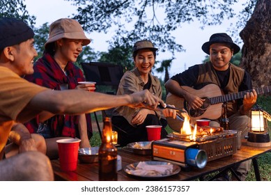 Happy asian diverse group friends enjoy drinking a beer together. They feeling relaxed and refreshing while camping in the nature at night. Recreation and journey outdoor activity lifestyle. - Powered by Shutterstock