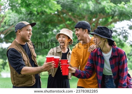 Happy asian diverse group friends enjoy drinking a beer together. They feeling relaxed and refreshing while camping in the nature. Recreation and journey outdoor activity lifestyle.