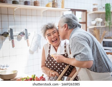 Happy Asian Elder Senior Couple Cooking Fresh Meal In Kitchen At Home.