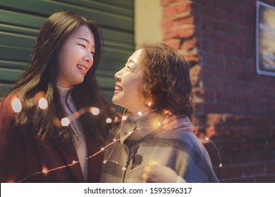 Happy asian elderly mother and adult daughter looking at each other at Portland Pearl district night