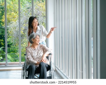 Happy Asian elderly woman, mother or grandparents on wheelchair taking care by caregiver, smiling young female, daughter or grandchild, look out the window, supporting at home, senior healthcare. - Powered by Shutterstock