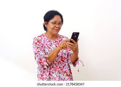 Happy Asian Elderly Woman Standing While Holding And Operating Her Cellular Phone. Isolated On White