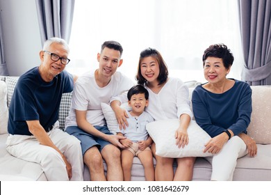 Happy Asian Extended Family Sitting On Sofa Together, Posing For Group Photos