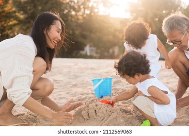 Happy Asian Family Building Sand Castle On The Sea Beach.