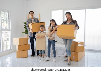 Happy Asian family with cardboard boxes in new house at moving day