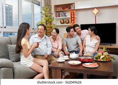 Happy Asian Family Celebrating Chinese New Year At Home; Couplets With Best Wishes For The New Year In The Background