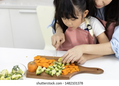 Happy Asian Family Close Up Of Mother And Child Daughter Are Preparing The Salad And Cutting Vegetables. Cooking Food In Kitchen At Home. Healthy Food Concept