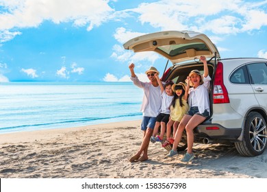 Happy Asian Family At Consisting Father, Mother, Son And Daughter Having Fun In Summer Vacation On The Beach With Sitting On Hatchback Car. Family Summer And Holiday Travel Concept.