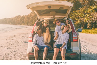 Happy Asian Family At Consisting Father, Mother, Son And Daughter Having Fun In Summer Vacation On The Beach With Sitting On Hatchback Car. Family Summer And Holiday Travel Concept.