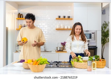 Happy Asian Family Couple Enjoy Cooking Pasta And Making Salad With Talking Together In The Kitchen At Home. Husband And Wife Having Dinner Party Celebration Eating Food Together On Holiday Vacation