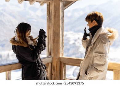 Happy Asian family couple enjoy outdoor lifestyle using digital camera taking picture with beautiful nature of forest mountain in snow during road trip travel in Japan on winter holiday vacation. - Powered by Shutterstock