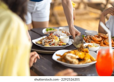 Happy Asian family couple and little kids travel ocean on summer holiday vacation. Waitress serving food and drink to customers on the table at beach restaurant at tropical island beach in sunny day. - Powered by Shutterstock
