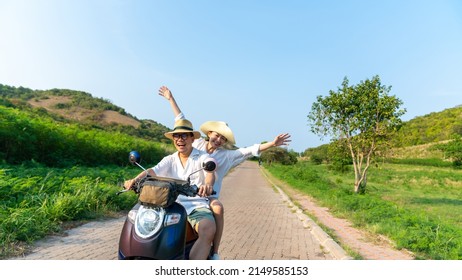 Happy Asian Family Couple Riding Motorcycle Together While Travel On Tropical Island Mountain Road In Summer Sunny Day. Husband And Wife Enjoy Outdoor Lifestyle On Holiday Travel Beach Vacation