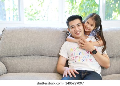 Happy Asian Family Daughter Hugging Father On Grey Sofa In Living Room With Happy Smiling Face (lifestyle Concept)