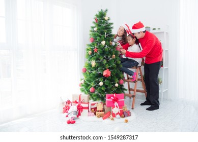 Happy Asian Family Decorating Christmas Tree Together At Home.