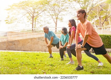 Happy Asian family, elderly parents and daughter, son, healthy care, warm up, flexible knee muscles, simple exercise before running in garden of stadium on sunny morning : Selected focus  - Powered by Shutterstock