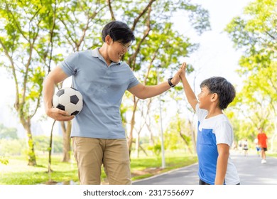 Happy Asian family enjoy and fun outdoor lifestyle travel together on summer holiday vacation. Father playing football or soccer with little son at public park in the city. Family relationship concept - Powered by Shutterstock