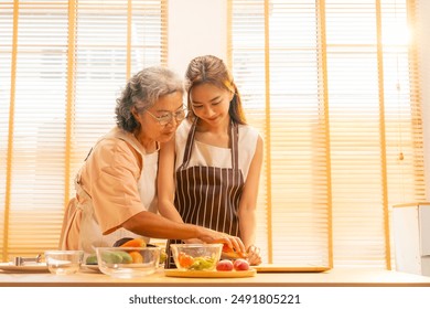 Happy Asian family enjoy and fun indoor healthy lifestyle cooking and having dinner together at home. Senior mature mother teaching adult daughter making vegan food vegetables salad in the kitchen. - Powered by Shutterstock