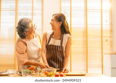 Happy Asian family enjoy and fun indoor healthy lifestyle cooking and having dinner together at home. Senior mature mother teaching adult daughter making vegan food vegetables salad in the kitchen. - Powered by Shutterstock