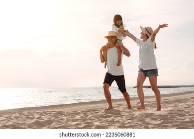 Happy asian family enjoy the sea beach at consisting father, mother and daughter having fun playing beach in summer vacation on the ocean beach. Happy family with vacations time lifestyle concept. - Powered by Shutterstock