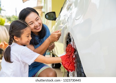 Happy asian family enjoy splashing water and washing car, - Powered by Shutterstock