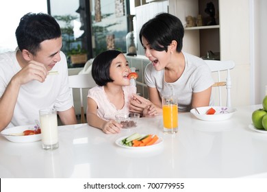 Happy Asian Family Enjoying A Healthy Snack At Home.