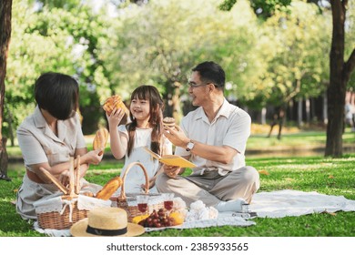 Happy Asian family enjoying picnic outing in the summer outdoors at the park - Powered by Shutterstock