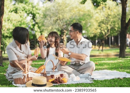 Happy Asian family enjoying picnic outing in the summer outdoors at the park