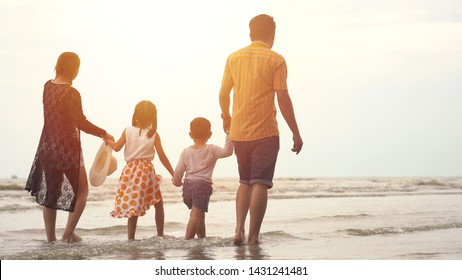 Happy asian family enjoying walk on the beach