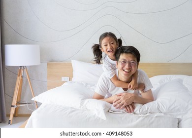 Happy Asian Family Father And Daughter Relaxing And Smiling On White Bed