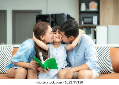 Happy Asian Family With Father And Mother Kiss In Their Daughter Cheek Together While Sitting In Living Room At Home. Love Emotion, Smiling Face, Enjoying, Joyful.