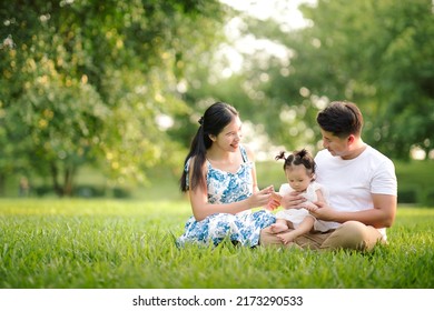 Happy Asian family father, mother, and little child daughter playing in the park enjoying the beautiful nature at sunset, Happy family holidays concept.