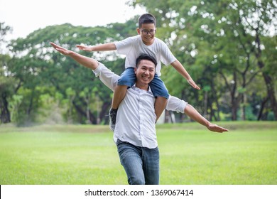 happy asian Family .Father and son runing , playing and stretching out hands together in the park . boy is sitting on shoulders dad . kid and parents outside. flying - Powered by Shutterstock