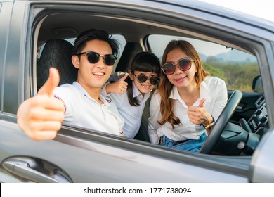 Happy Asian Family With Father Thumb Up And Mother And Daughter Wear Sunglass In Compact Car Are Smiling And Driving For Travel On Vacation. Car Insurance Or Rental 
