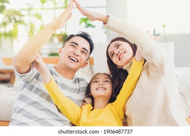 Happy Asian Family Forming House Roof With Their Hands At Home