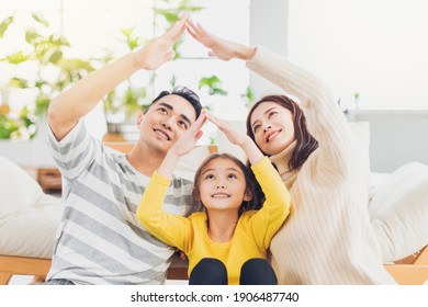 Happy Asian Family Forming House Roof With Their Hands At Home