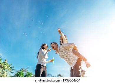 Happy asian family in the garden They are having fun playing and blowing bubbles. - Shutterstock ID 1936804654