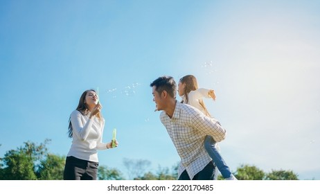 Happy Asian Family In The Garden They Are Having Fun Playing And Blowing Bubbles. And Enjoyed Ourselves Together In The Green Garden. Family Enjoying Sunny Fall Day In Nature.