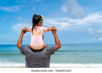 Happy Asian Family Grandfather Carrying And Playing With Little Grandchild Girl While Walking On The Beach On Summer Vacation. Senior Man And Child Girl Kid Enjoy Outdoor Lifestyle Together At The Sea