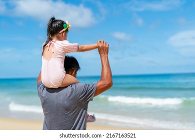 Happy Asian Family Grandfather Carrying And Playing With Little Grandchild Girl While Walking On The Beach On Summer Vacation. Senior Man And Child Girl Kid Enjoy Outdoor Lifestyle Together At The Sea