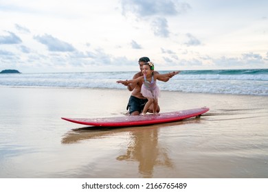 Happy Asian Family Grandfather Teaching Little Grandchild Girl Surfing On Surfboard At The Beach. Senior Man And Little Girl Enjoy Outdoor Activity Lifestyle Water Sport Surfing On Summer Vacation