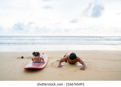 Happy Asian Family Grandfather Teaching Little Grandchild Girl Surfing On Surfboard At The Beach. Senior Man And Little Girl Enjoy Outdoor Activity Lifestyle Water Sport Surfing On Summer Vacation