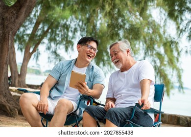 Happy Asian family handsome man teach senior father using digital tablet for video call or online shopping on the beach in summer day. Father and son enjoy and having fun together in holiday vacation - Powered by Shutterstock