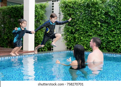 Happy Asian Family Have Fun On Swimming Pool At Summer Vacation Running And Jumping In The Pool.