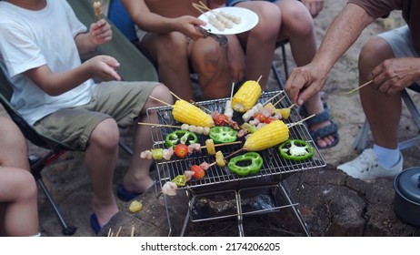 Happy Asian family having barbecue together. Cooking grilled bbq for dinner during camping on summer beach. - Powered by Shutterstock