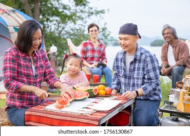 Happy Asian Family Having Fun While Eating Water Melon At A Picnic