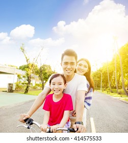 Happy Asian Family Having Fun In Park With Bicycle