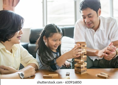 Happy Asian Family Having Fun Playing Jenga In The Living Room